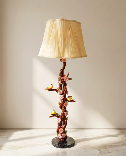 آباژور ایستاده کنارسالنی دستساز با پایه طرح شاخه و پرنده، شید پارچهای کرم و نور گرم در دکوراسیون پذیرایی